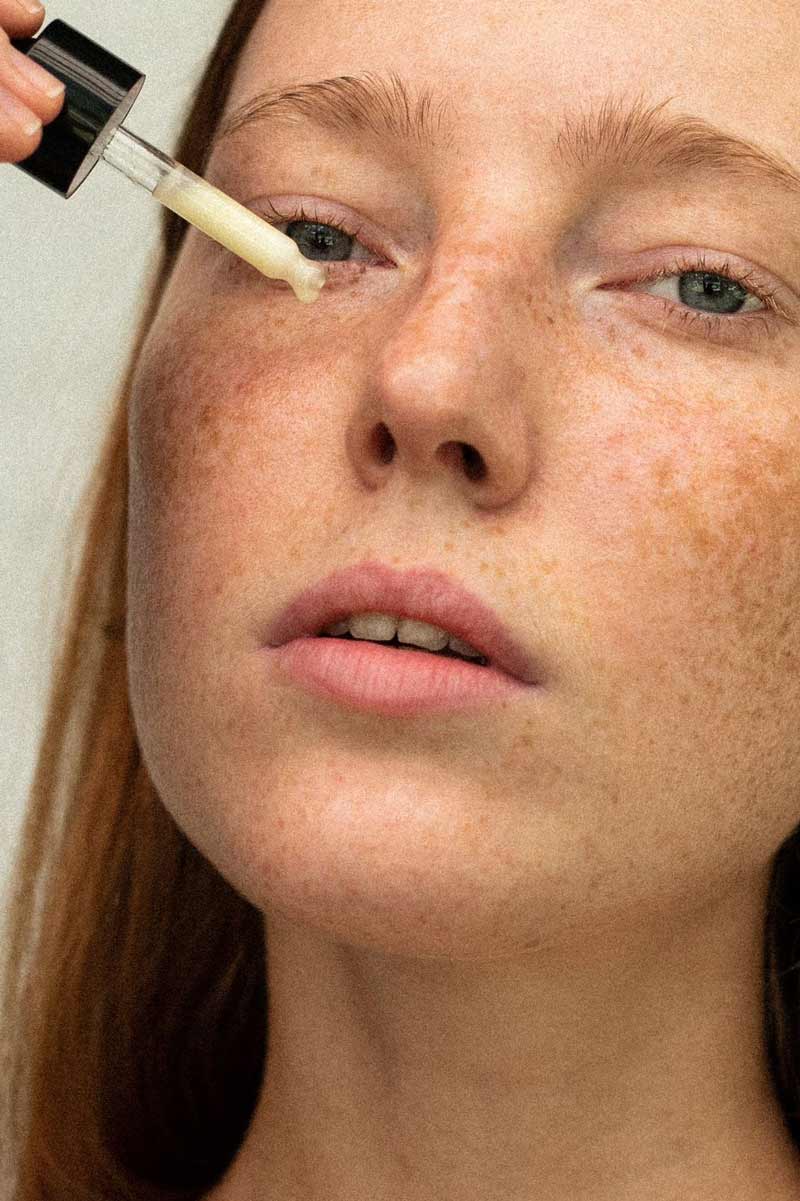 image of a young woman using fields of yarrow home made skincare products on her skin